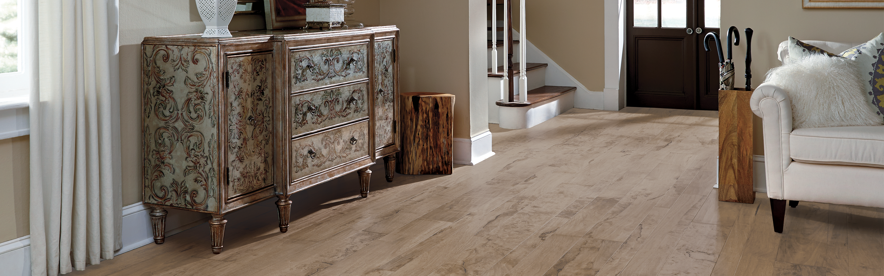 Wide plank hardwood floor entryway with stairs and cream couch 